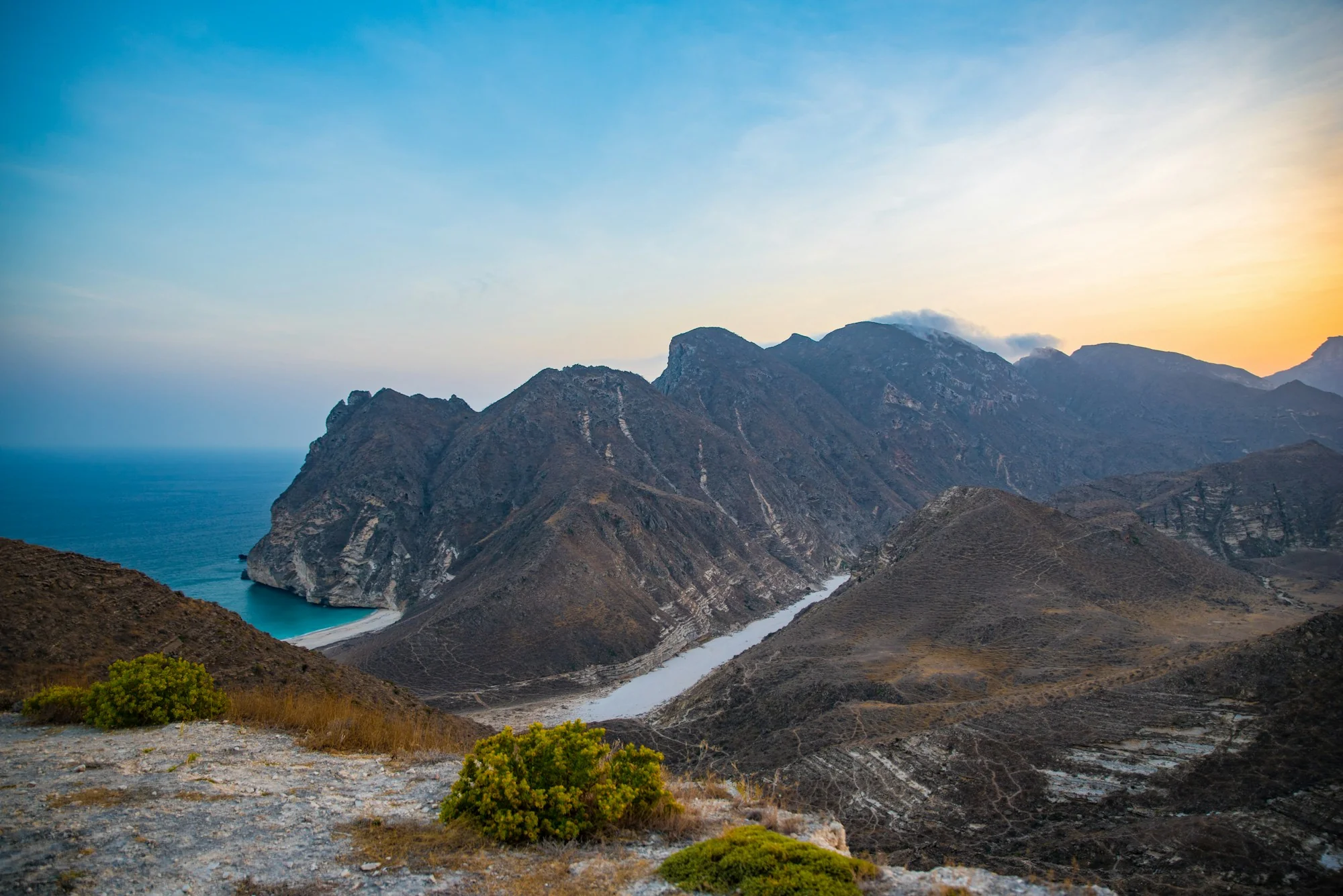Dramatic coastal mountains overlooking the sea in Oman at dusk.